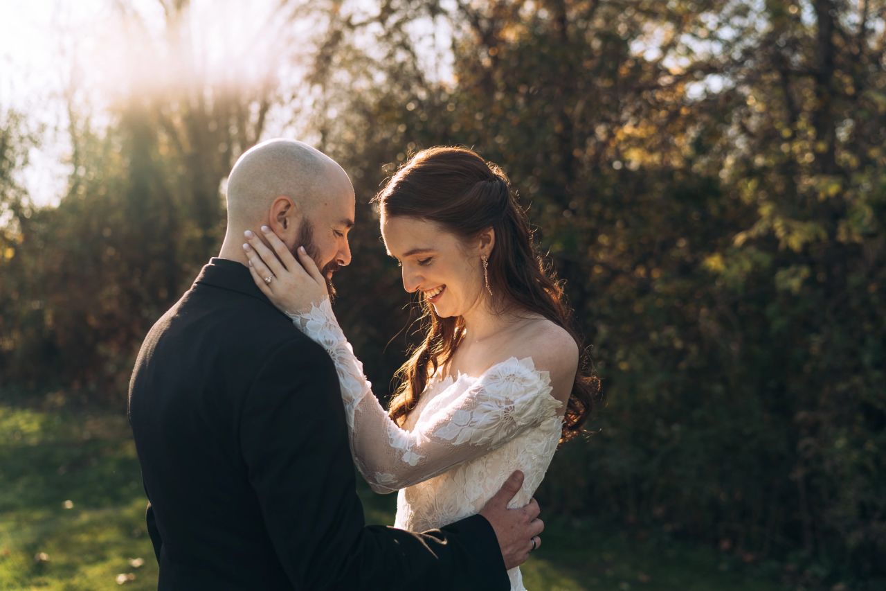 A new bride and groom hold each other in the glowing afternoon Fall light.